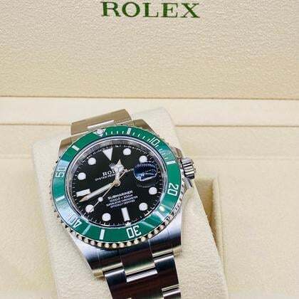 Rolex watch with green bezel and black dial on a beige background