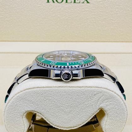Rolex watch with green bezel on a white cushion