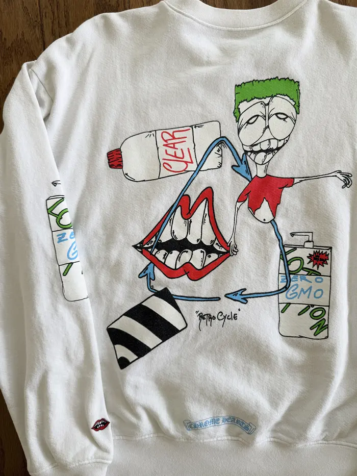 White long-sleeve shirt with colorful graphic design on a wooden surface